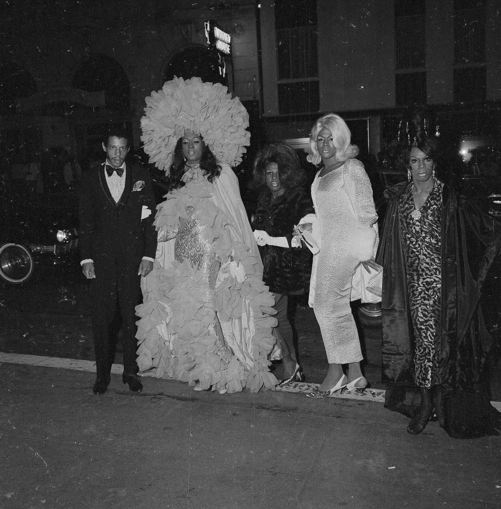 black-and-white photograph of people in fancy dresses and suits outside