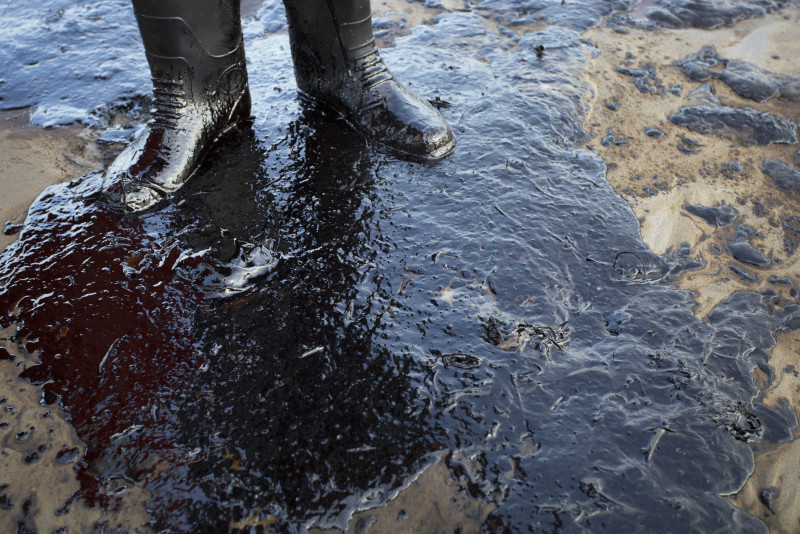 Oil surrounds the feet of local resident Morgan Miller as he patrols the beach for oiled wildlife on May 19, 2015. north of Goleta, California.