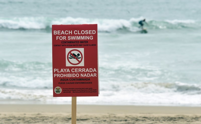 A surfer ignored a warning to stay out of the water in Manhattan Beach last week as much of coastline near Los Angeles was closed amid continuing cleanup efforts to remove an unidentified tarlike substance that began washing ashore after an oil spill near Santa Barbara.