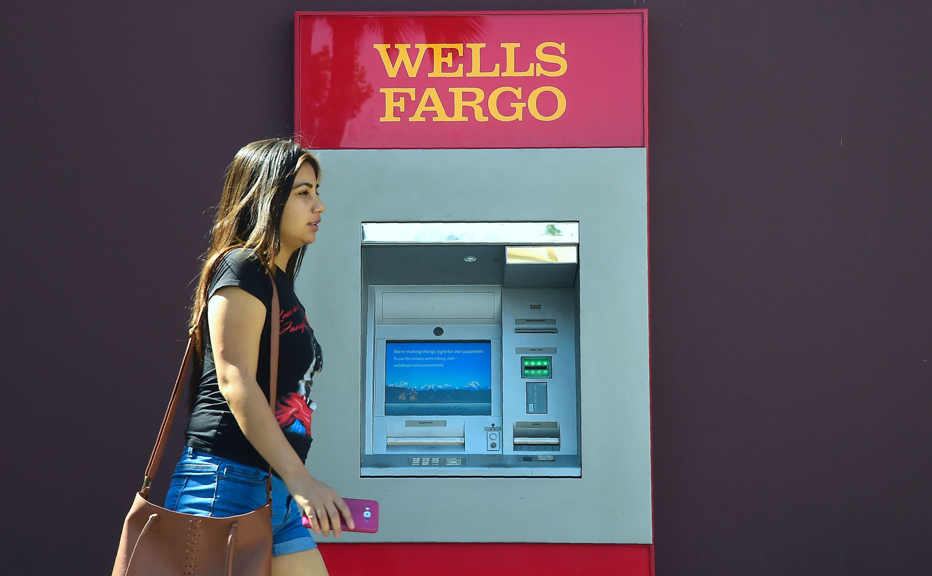 A woman walks past a Wells Fargo ATM in Pasadena on September 28, 2016. California Treasurer John Chiang said the state will suspend several banking relationships with Wells Fargo to sanction the firm following allegations of 'fleecing its customers.'