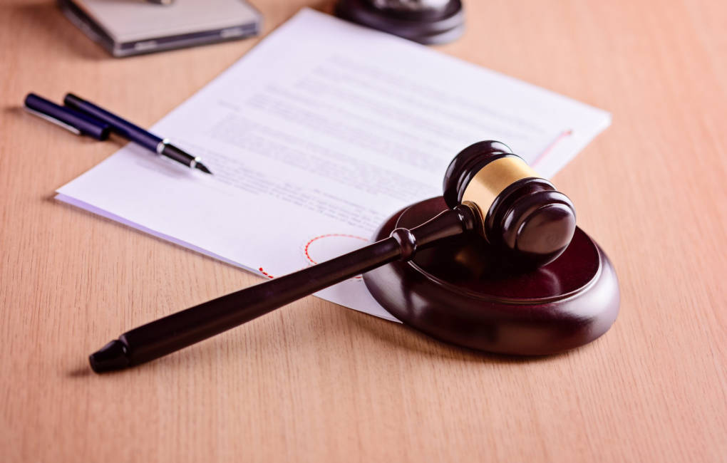 A gavel, pen and a piece of paper on a desk.
