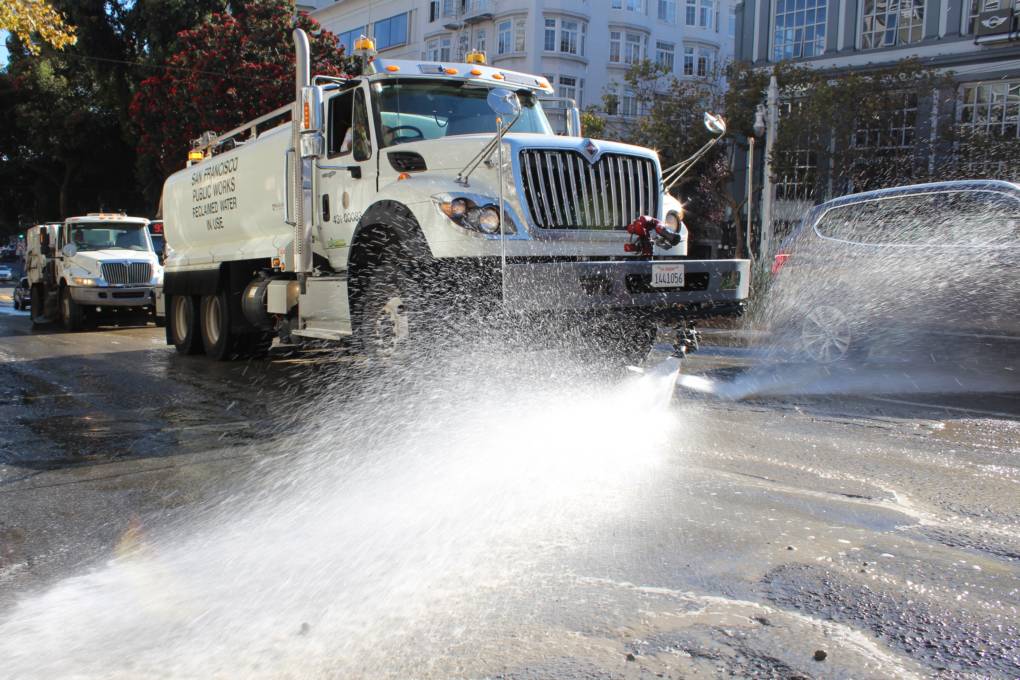 A flusher sprays the streets down with water.