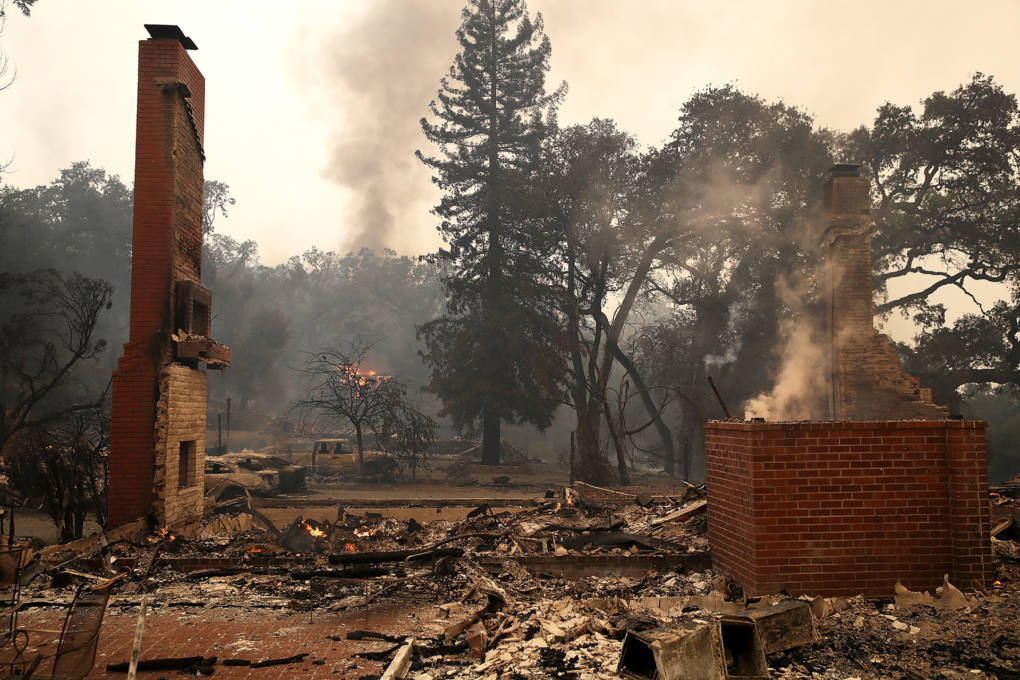 The smouldering remains of a structure, with two brick parts of the structure still standing.