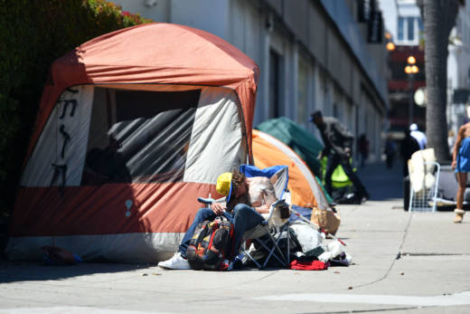 A homeless man sleeps in front of his tent along Van Ness Avenue in San Francisco.