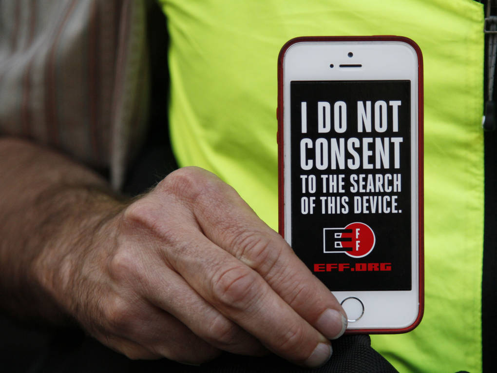 In this 2016 photo, a man holds up his iPhone during a rally in support of data privacy outside the Apple store in San Francisco. Watchdog groups that keep tabs on digital privacy rights are concerned that U.S. Customs and Border Protection agents are searching the phones and other digital devices of international travelers at border checkpoints in U.S. airports.