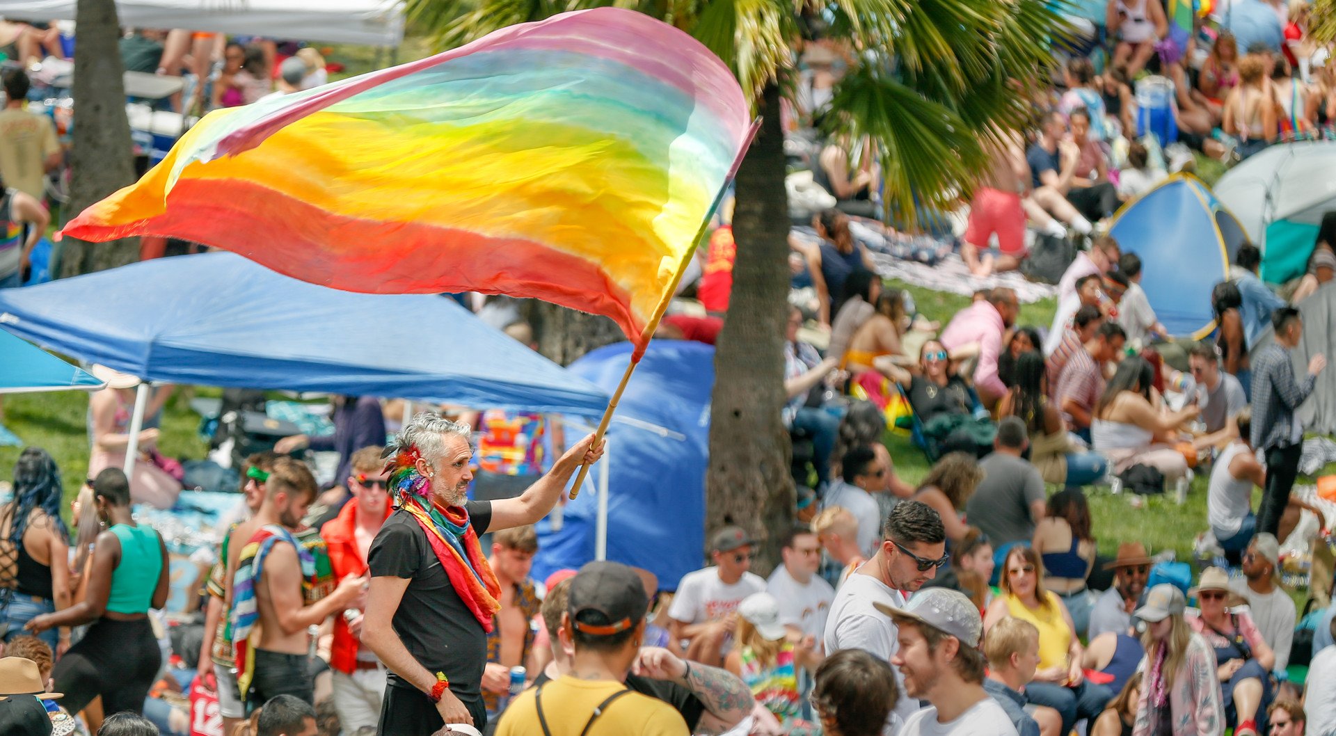 Man waves pride flag high during Pride festivities at Dolores Park