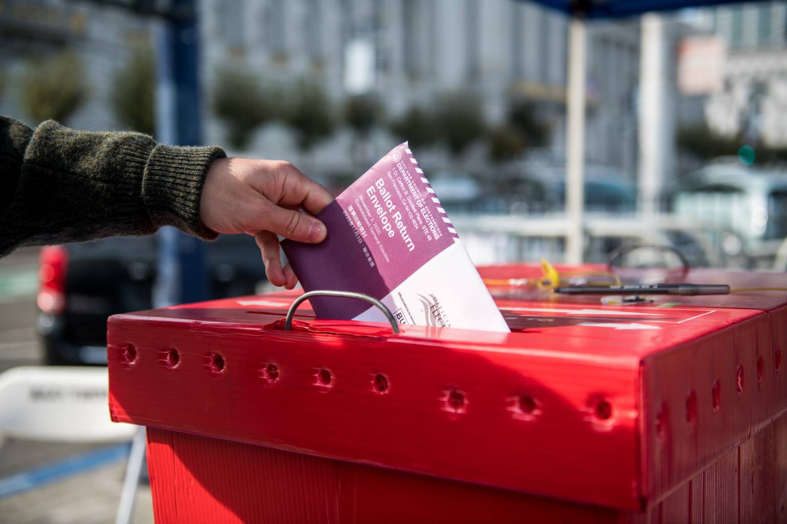 A ballot is placed in a red ballot box.