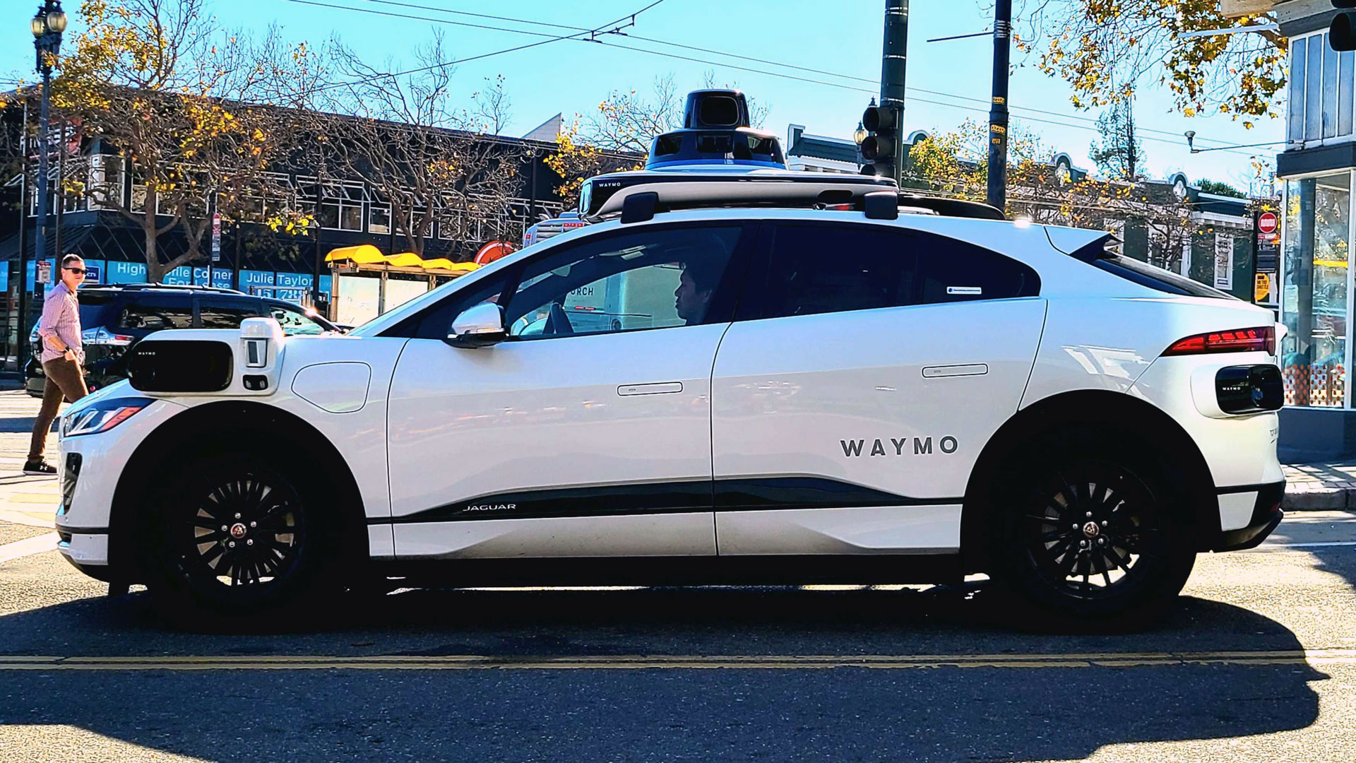 A white SUV with tech gadgets and cameras sticking out from the sides and roof waits at a stoplight in San Francisco's Castro neighborhood.