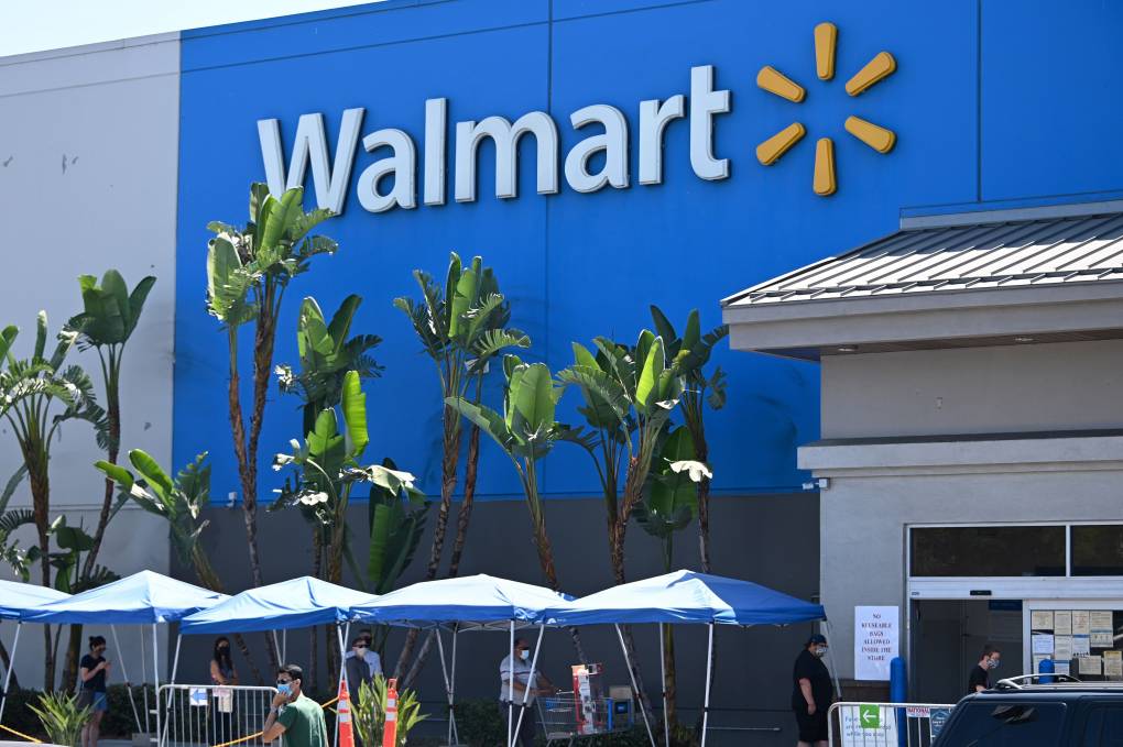 In front of the large Walmart store there are many palm trees and tents.