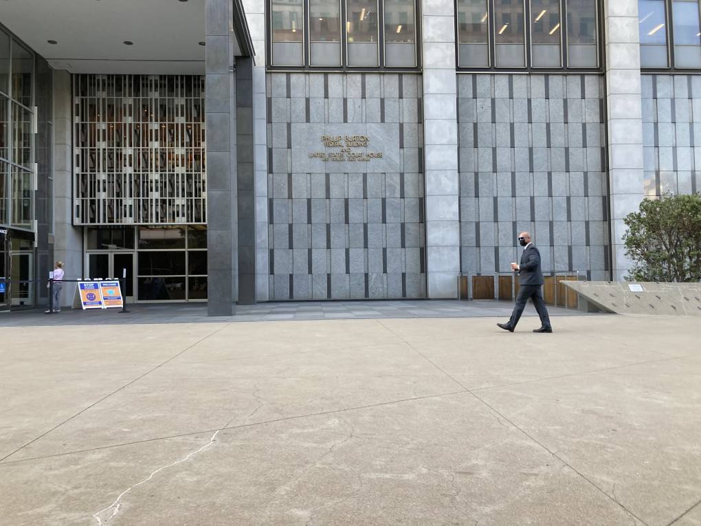 A man wearing a face mask and business suit walks into a building.
