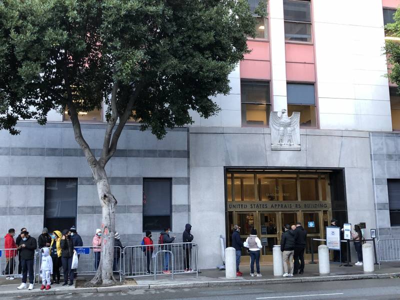 People stand in line outside of a court building.