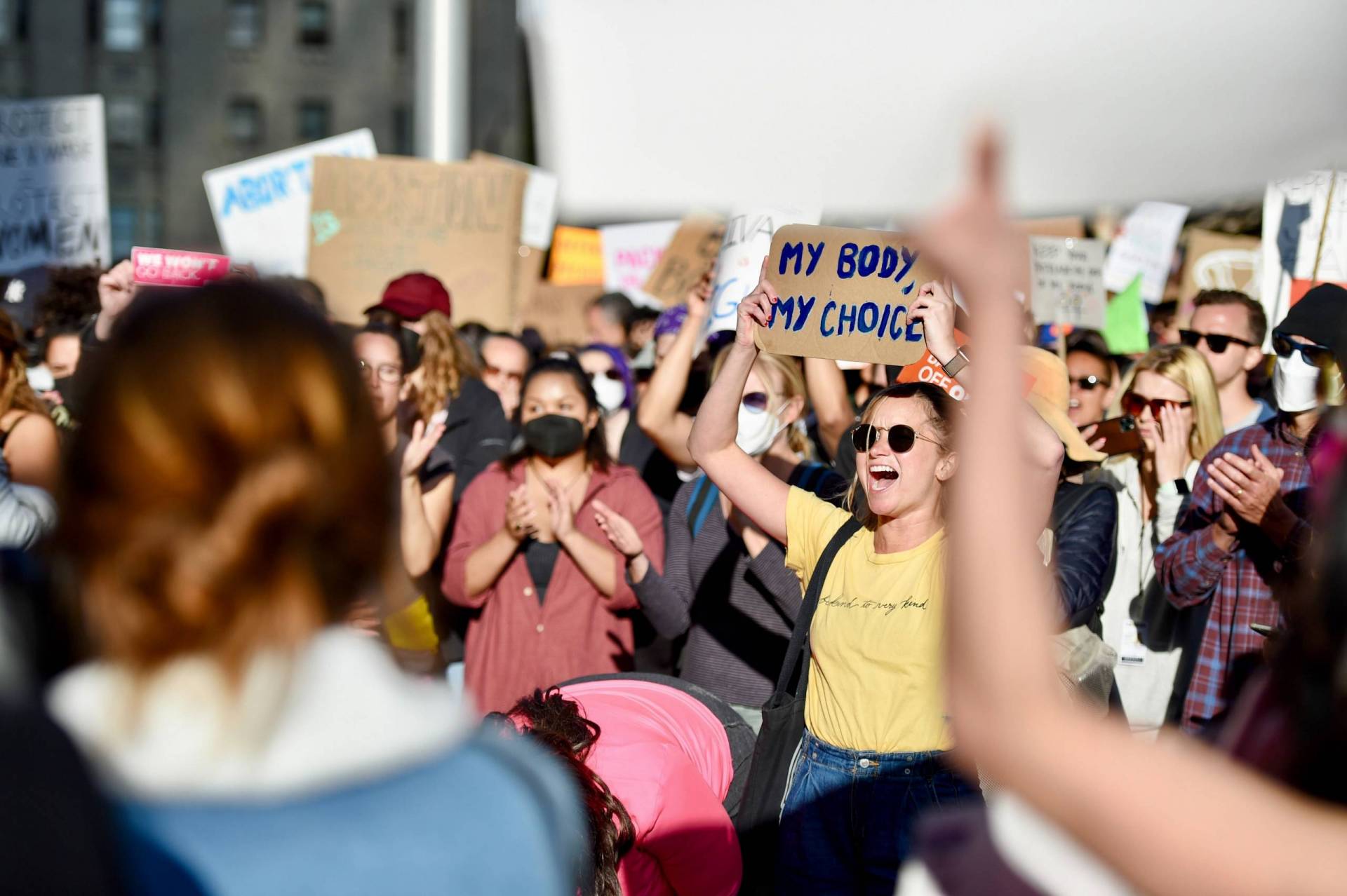 A large crowed assembles in downtown San Francisco. Many are chanting and holding up signs. One sign reads, "My body, my choice."