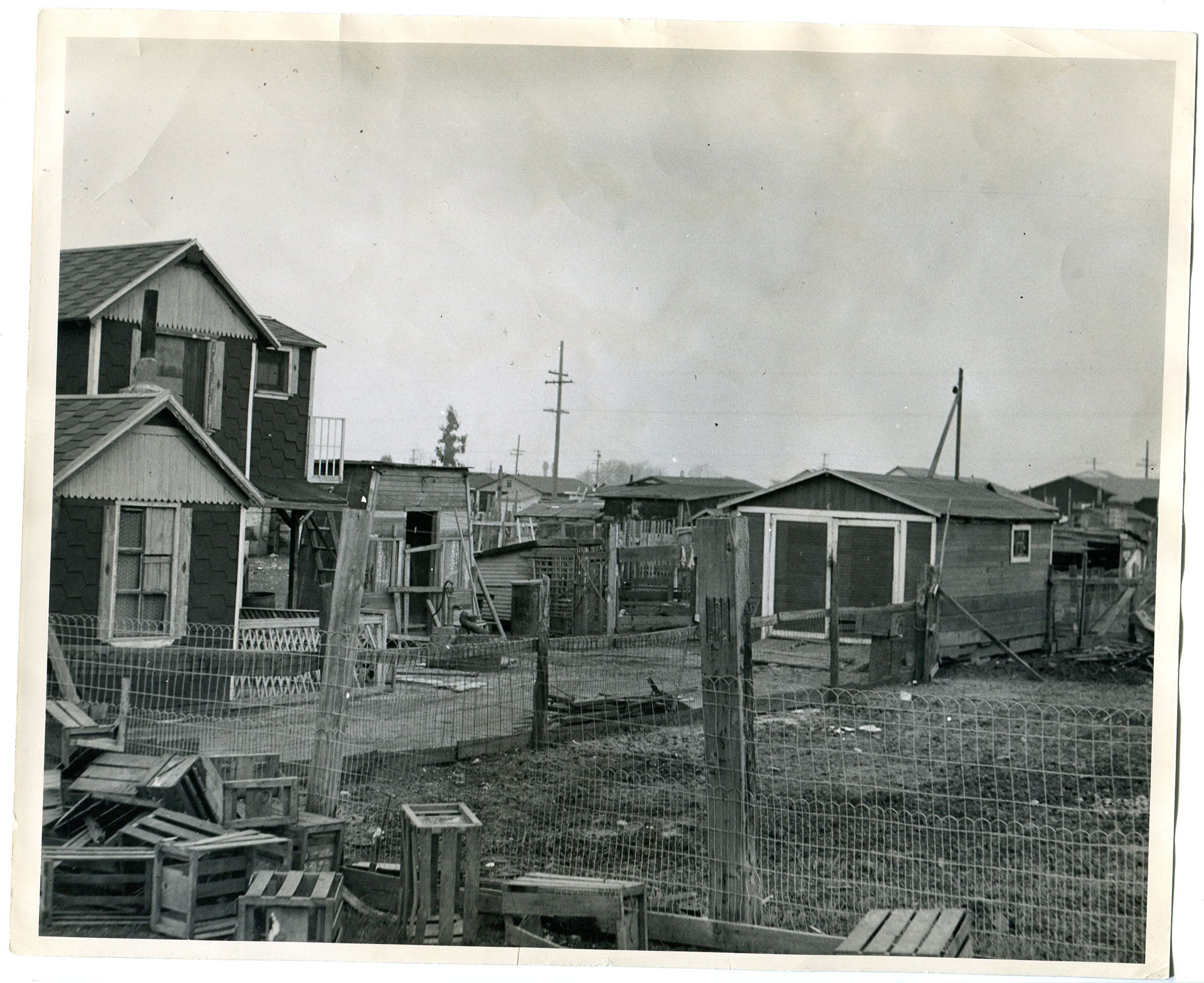 Black and white photograph of several wooden buildings including a home, a large shed or garage and several small structures.