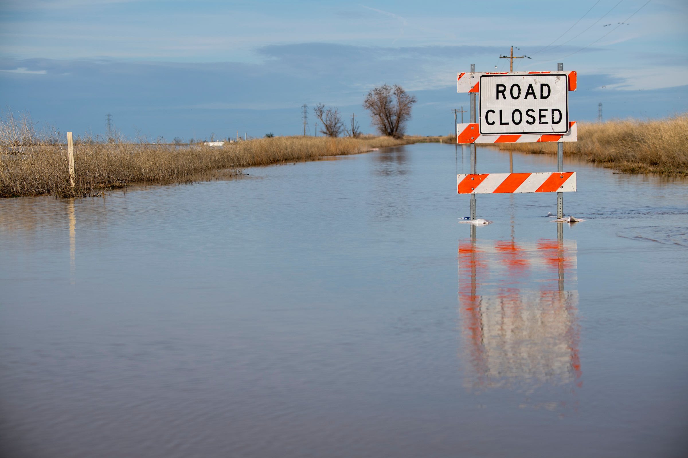A "road closed" sign is reflected in floodwater in California's Central Valley.