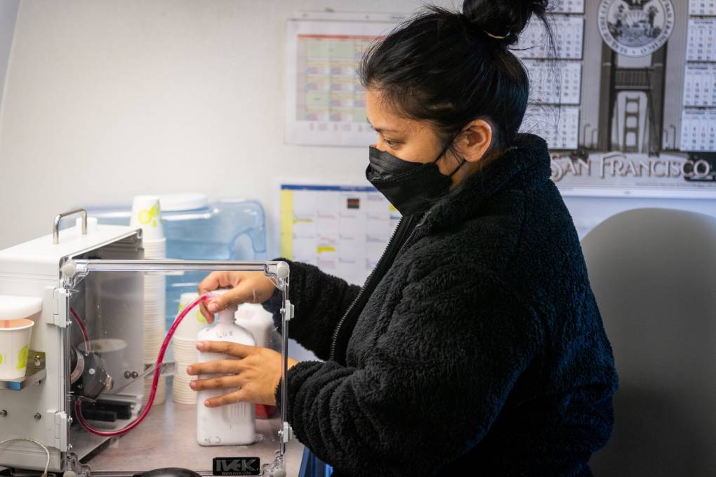 A nurse wearing a face mask fills medication.