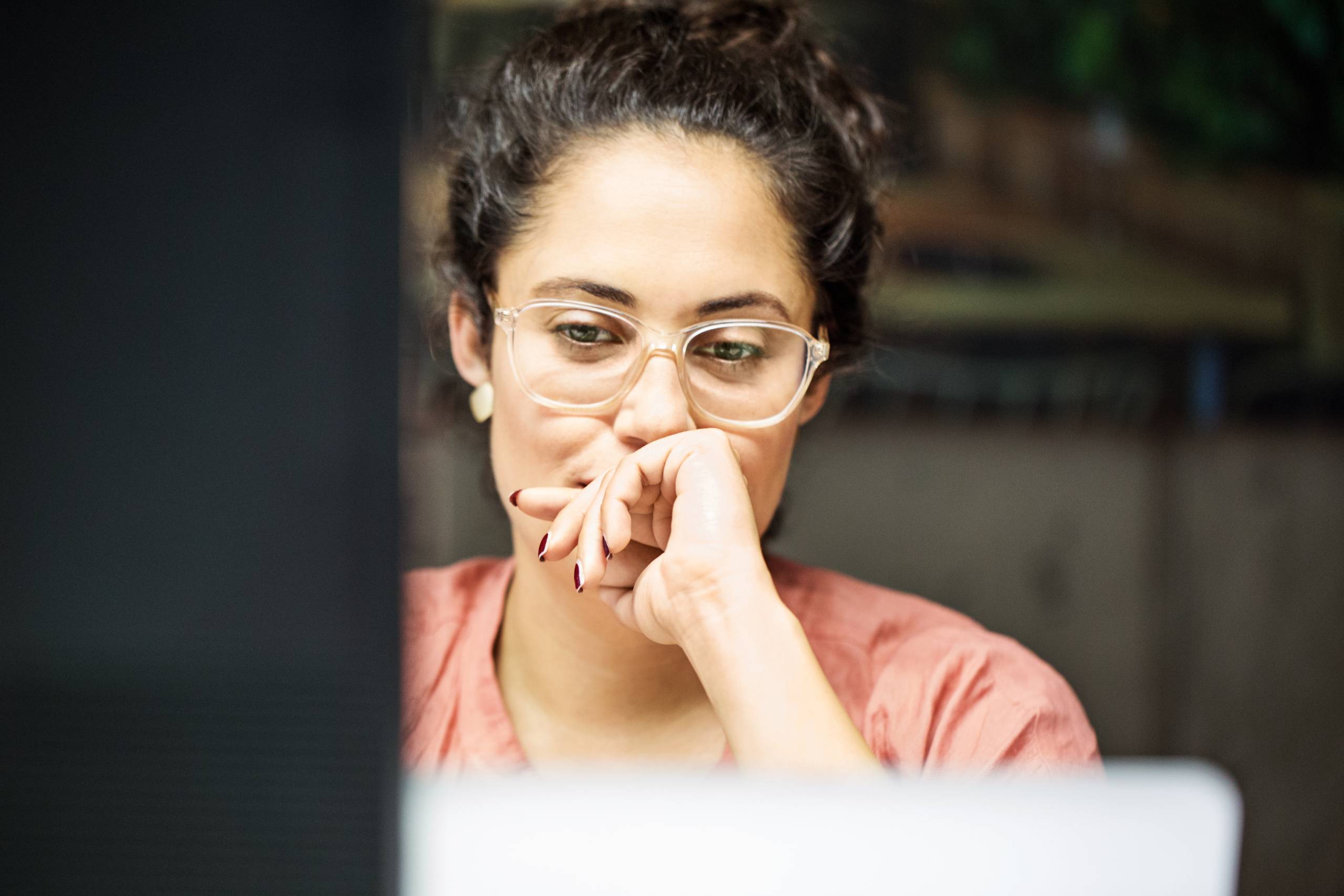 Young businesswoman looks at a computer screen thoughtfully.
