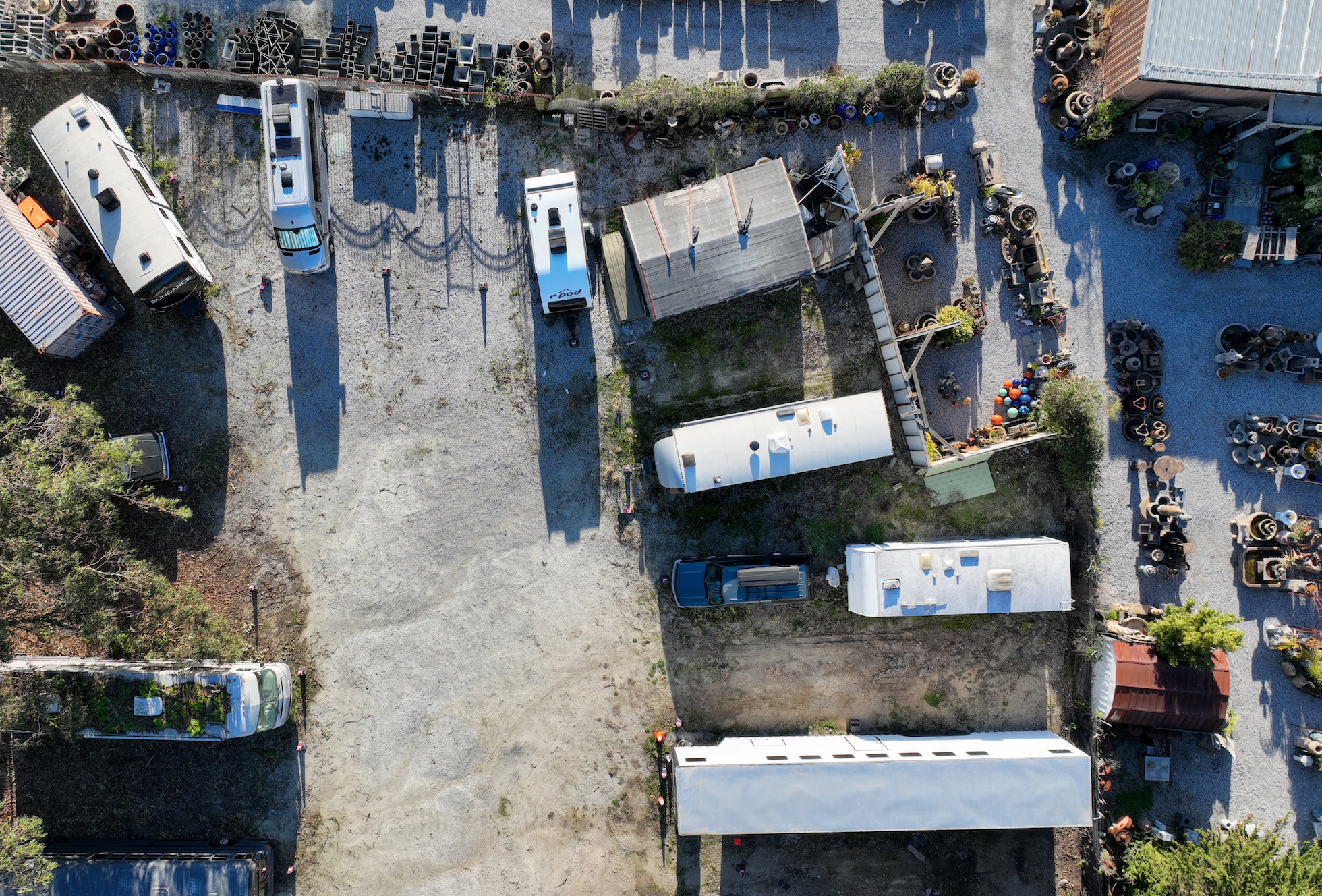A row of dilapidated trailers are seen from above in a dirt lot.