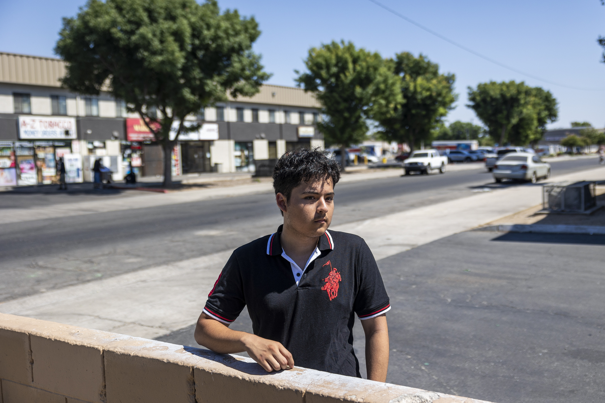 A person stands by a brick wall in front of a street.