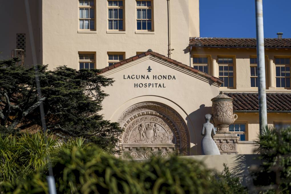 Signage reading Laguna Honda Hospital over the entryway to a large tile-roofed building.
