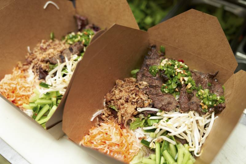 Takeout boxes filled with meat and vegetable dishes.