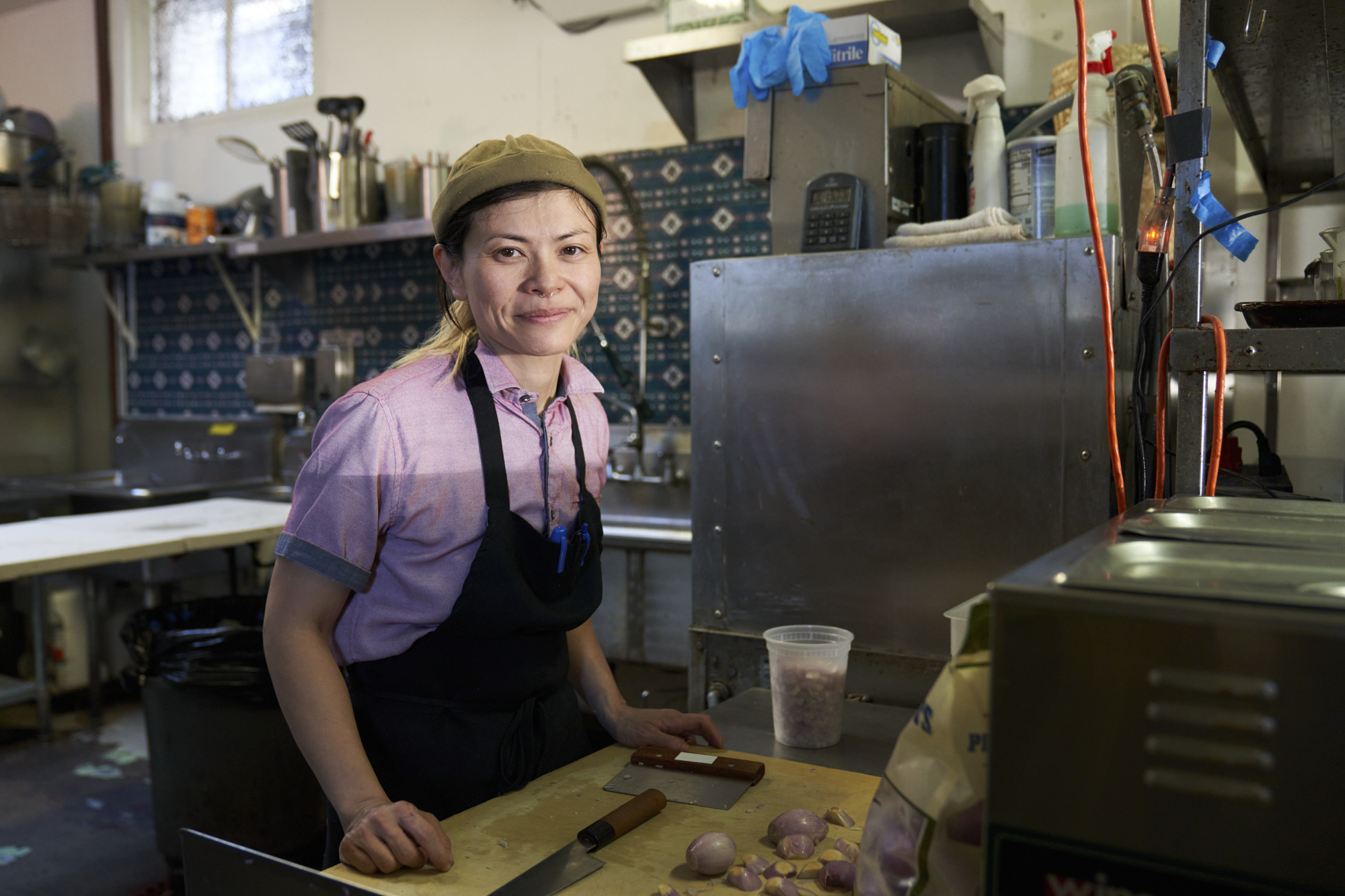 A person stands at a cutting board in a kitchen smiling.