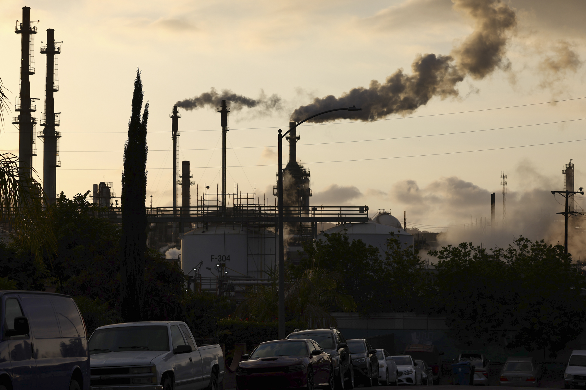 The silhouettes of several smokestacks emit fumes into the air.