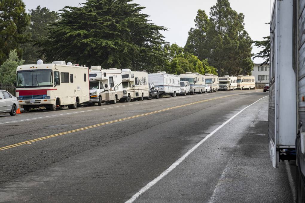 A row of RVs parked along a two-lane street.