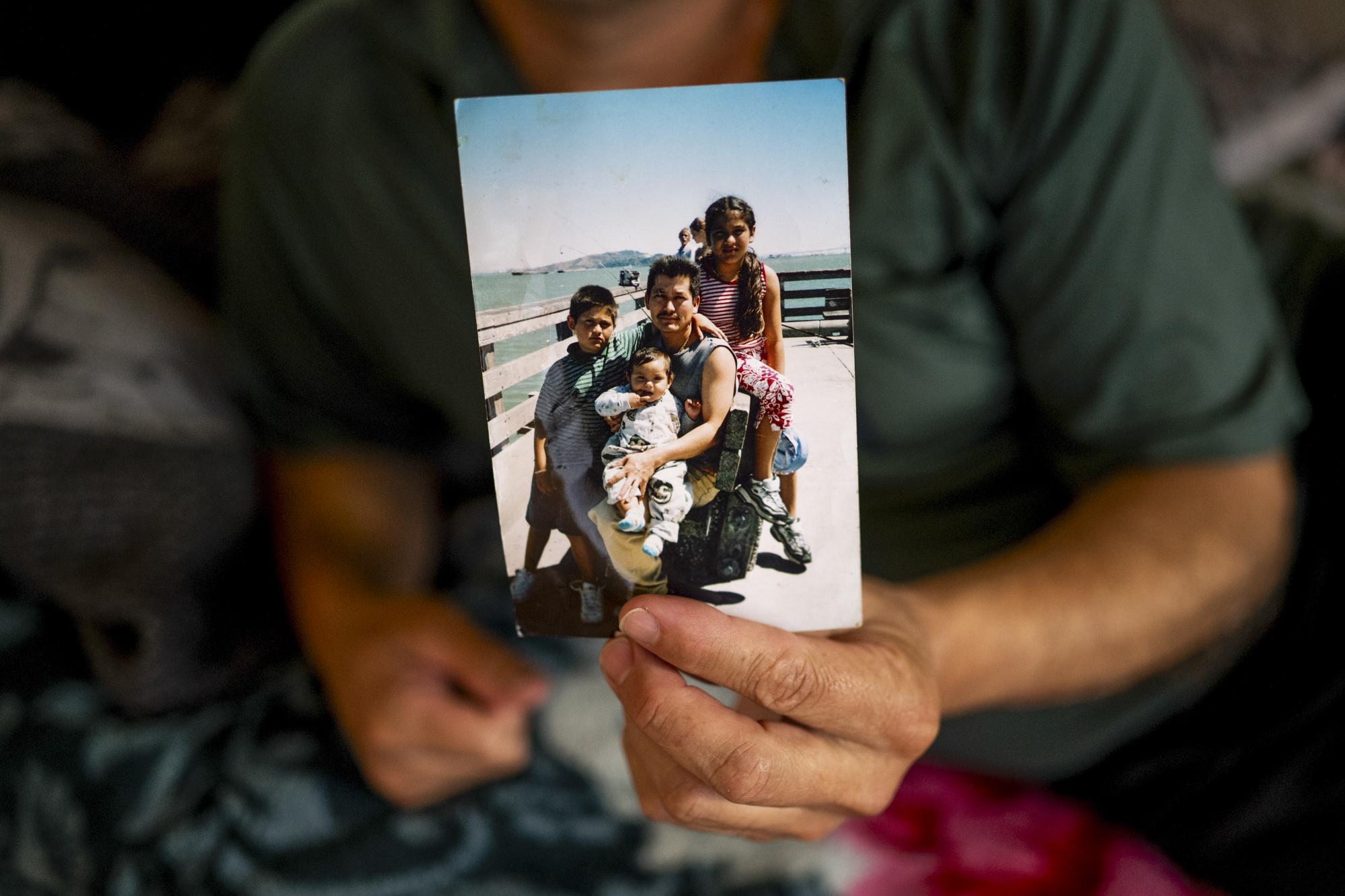 A hand holds a photo of an adult with three children.