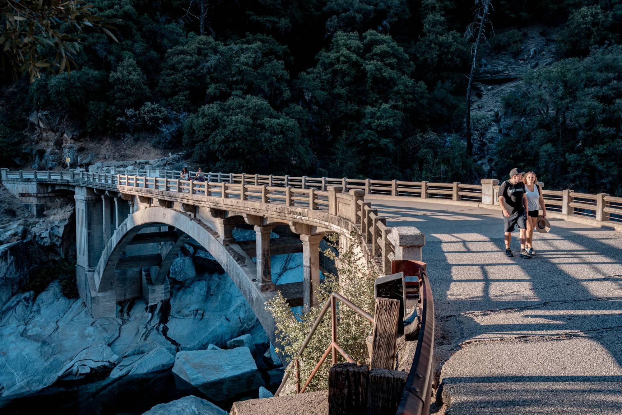 A photo of a bridge with two pairs of people walking.