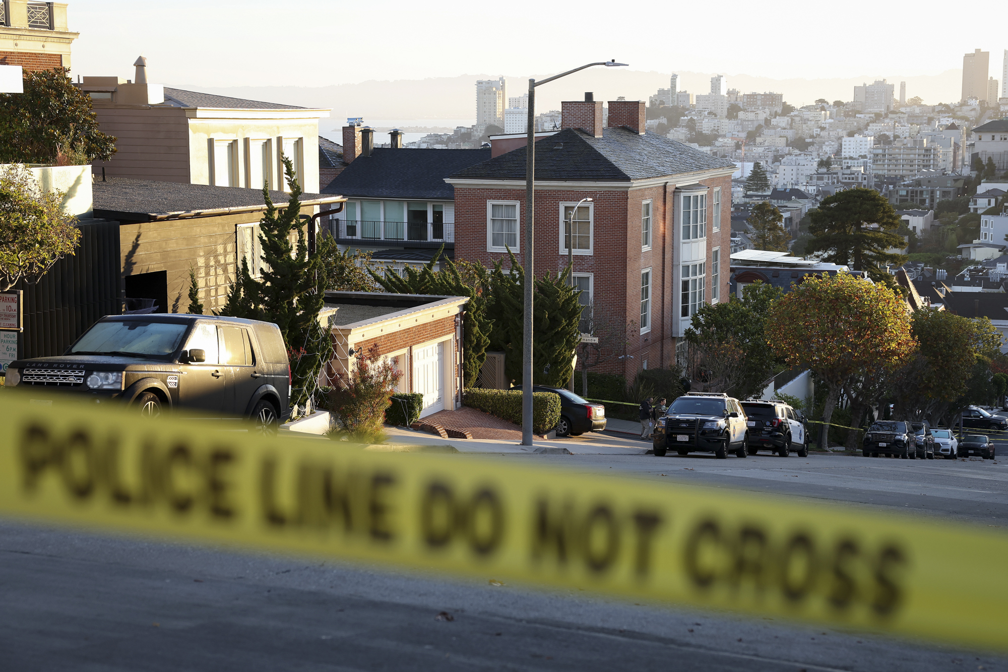 A brick house on a hill is seen from behind police caution tape.