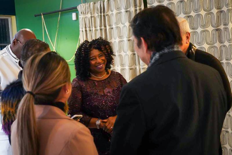 A Black woman smiles, surrounded by supporters.