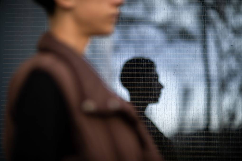 A photo of a woman standing in front of a silhouette of a younger person.