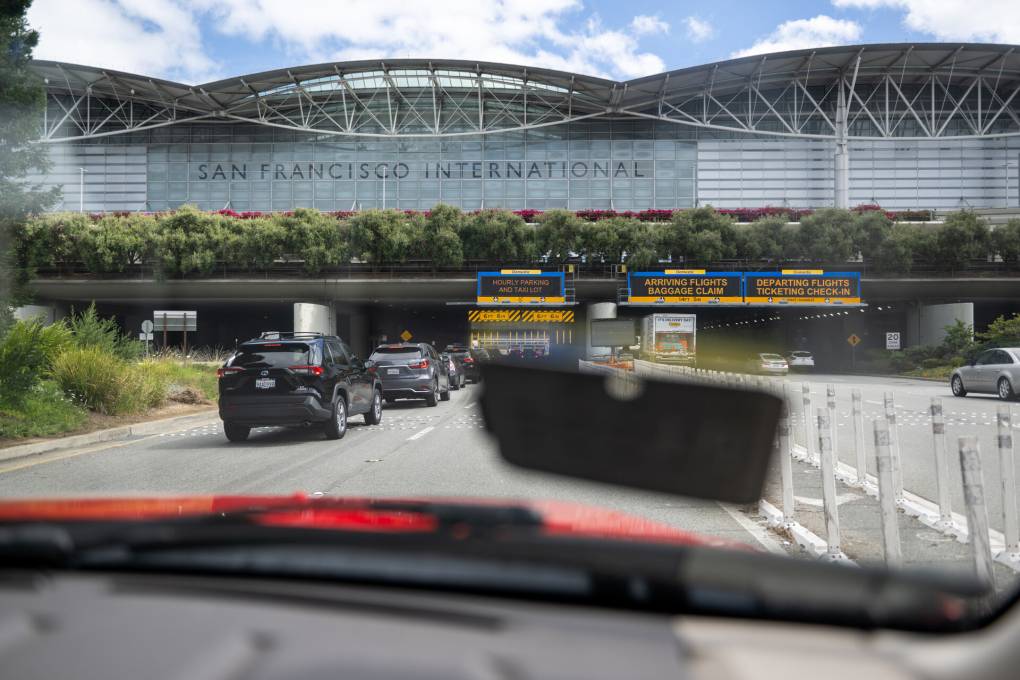 A driver's view of cars on a road moving towards a large building that says "San Francisco International."