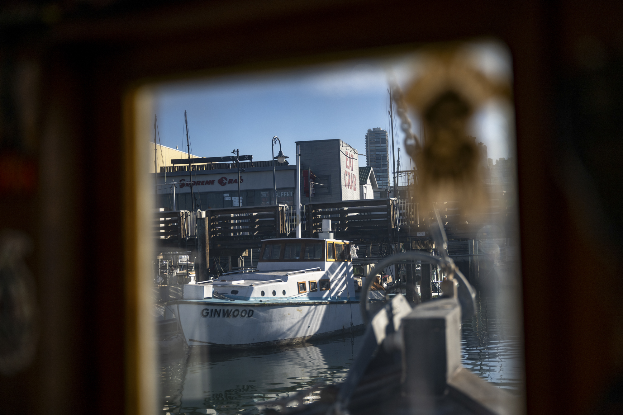 A boat docked in a harbor is seen through a window.
