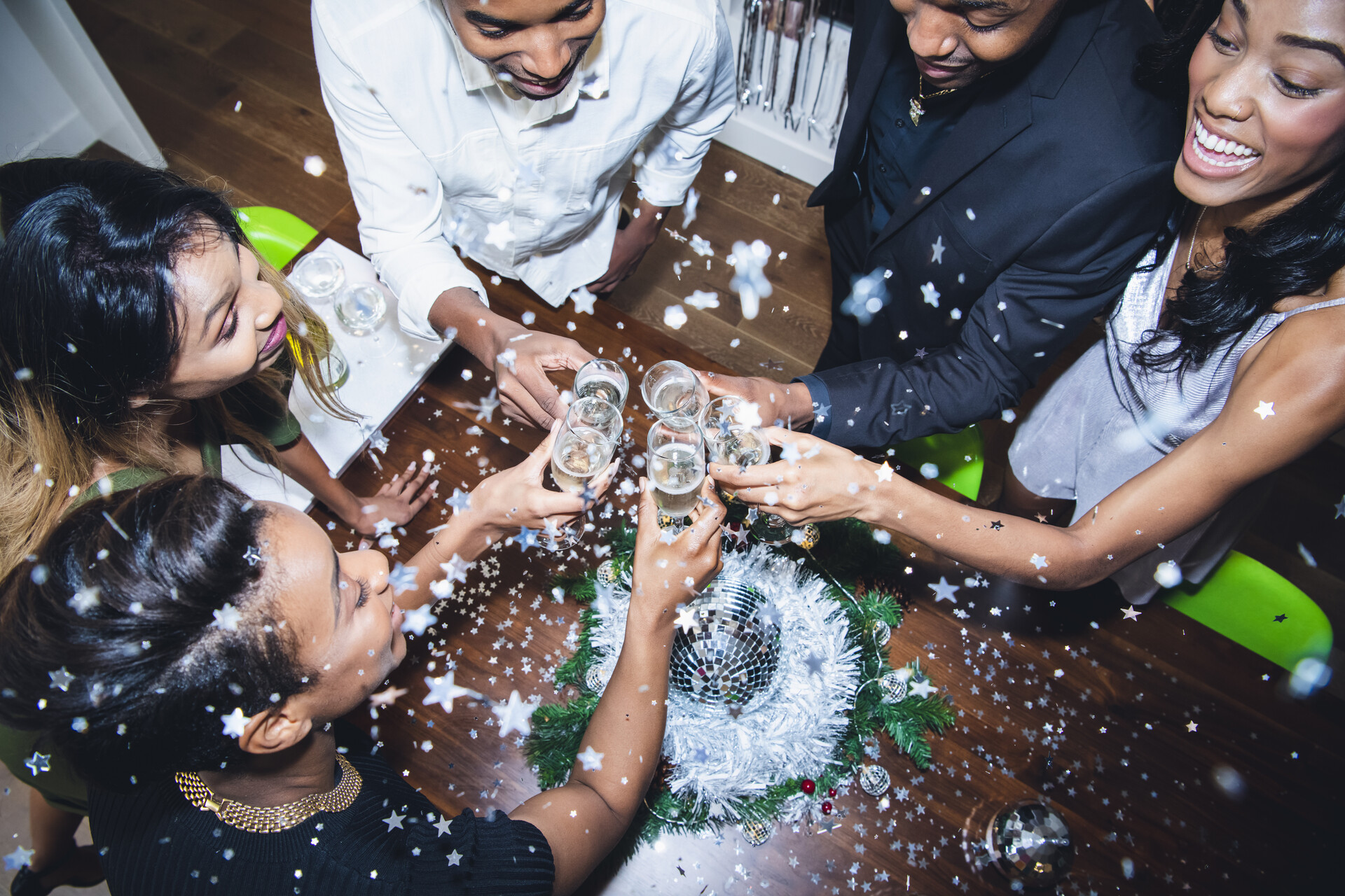 A photograph taken from above of a group of people "cheersing" their glasses at a New Year's Eve party