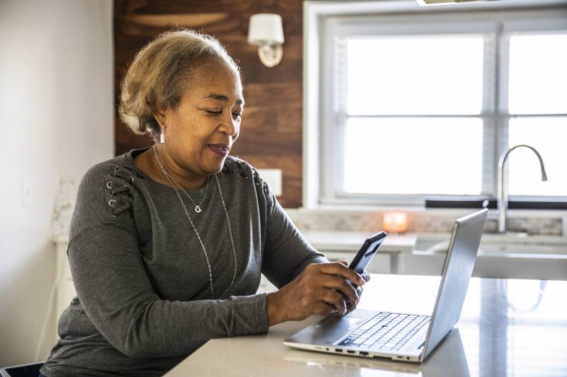 Portrait of a senior woman working using laptop in residential kitchen