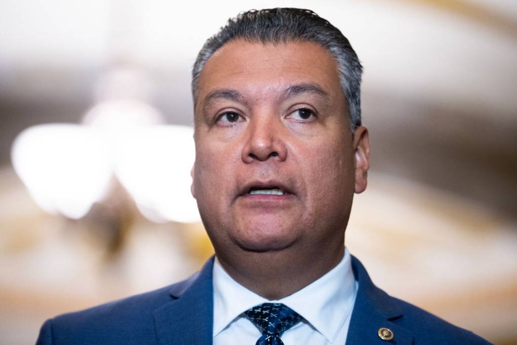 Headshot of a Latino man with blue suit and tie looking away from the camera.