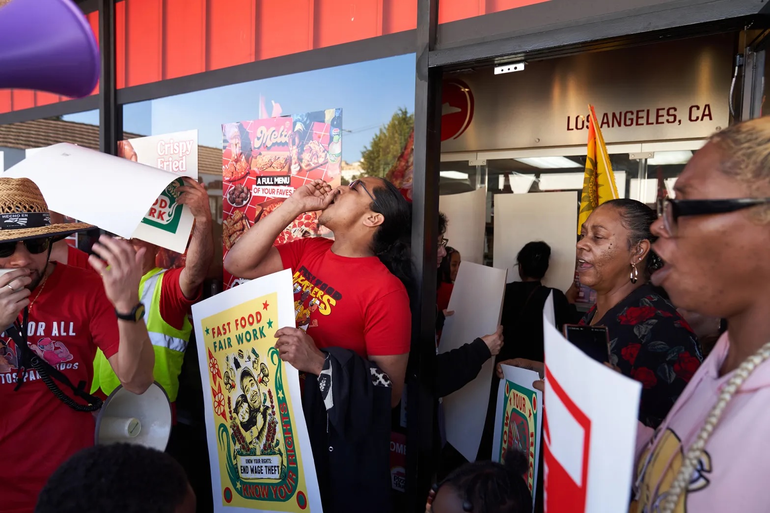 Protesters with signs outside a fast food restaurant.