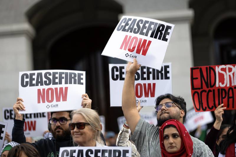 Several people hold signs that read "Ceasefire Now" outside.