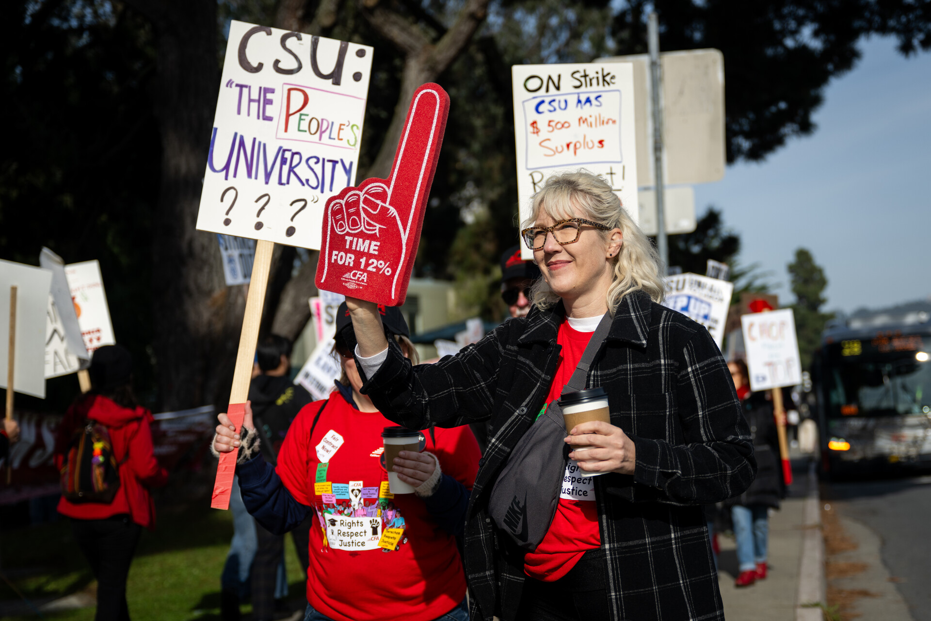 A woman with a sign stands in front of other people with protest signs.
