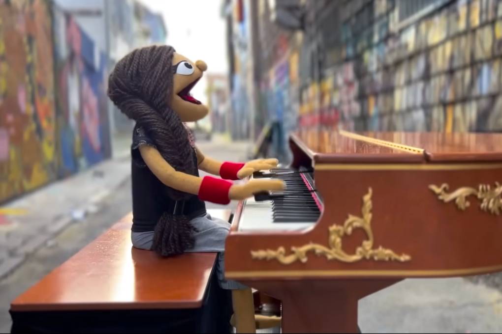 A puppet plays the piano in an outdoor setting.