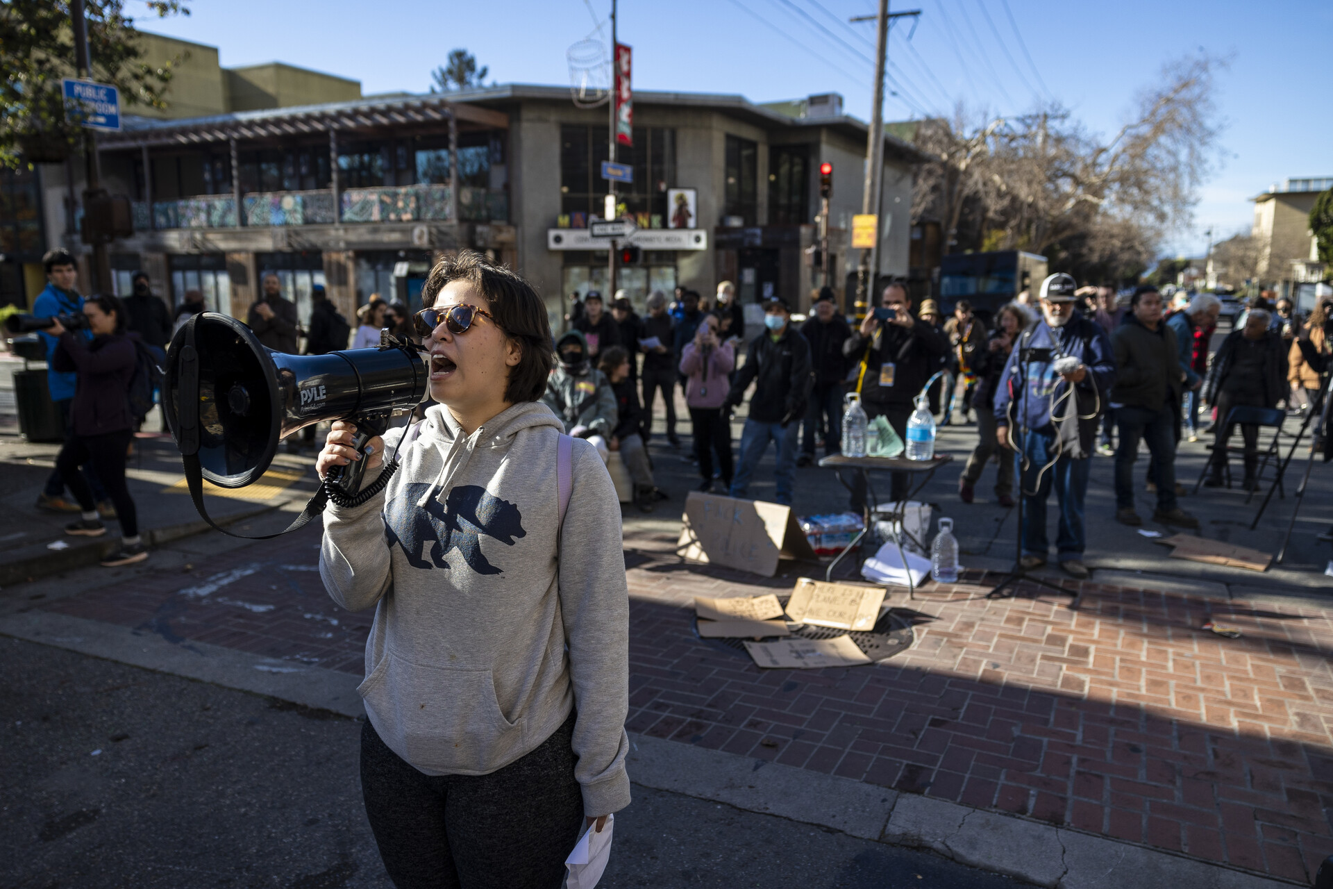 A woman holds a bullhorn with several people behind her outside.