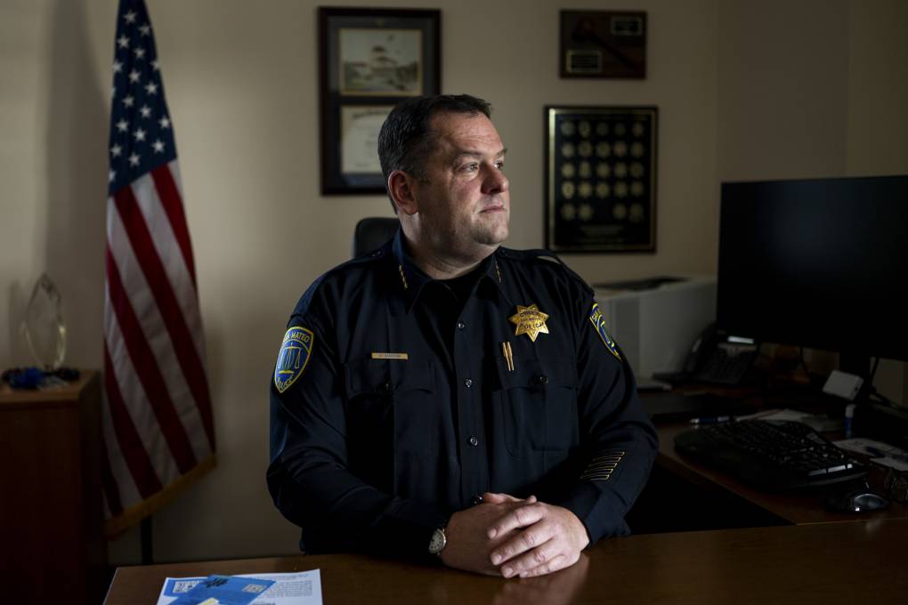 A police officer sits behind a desk.