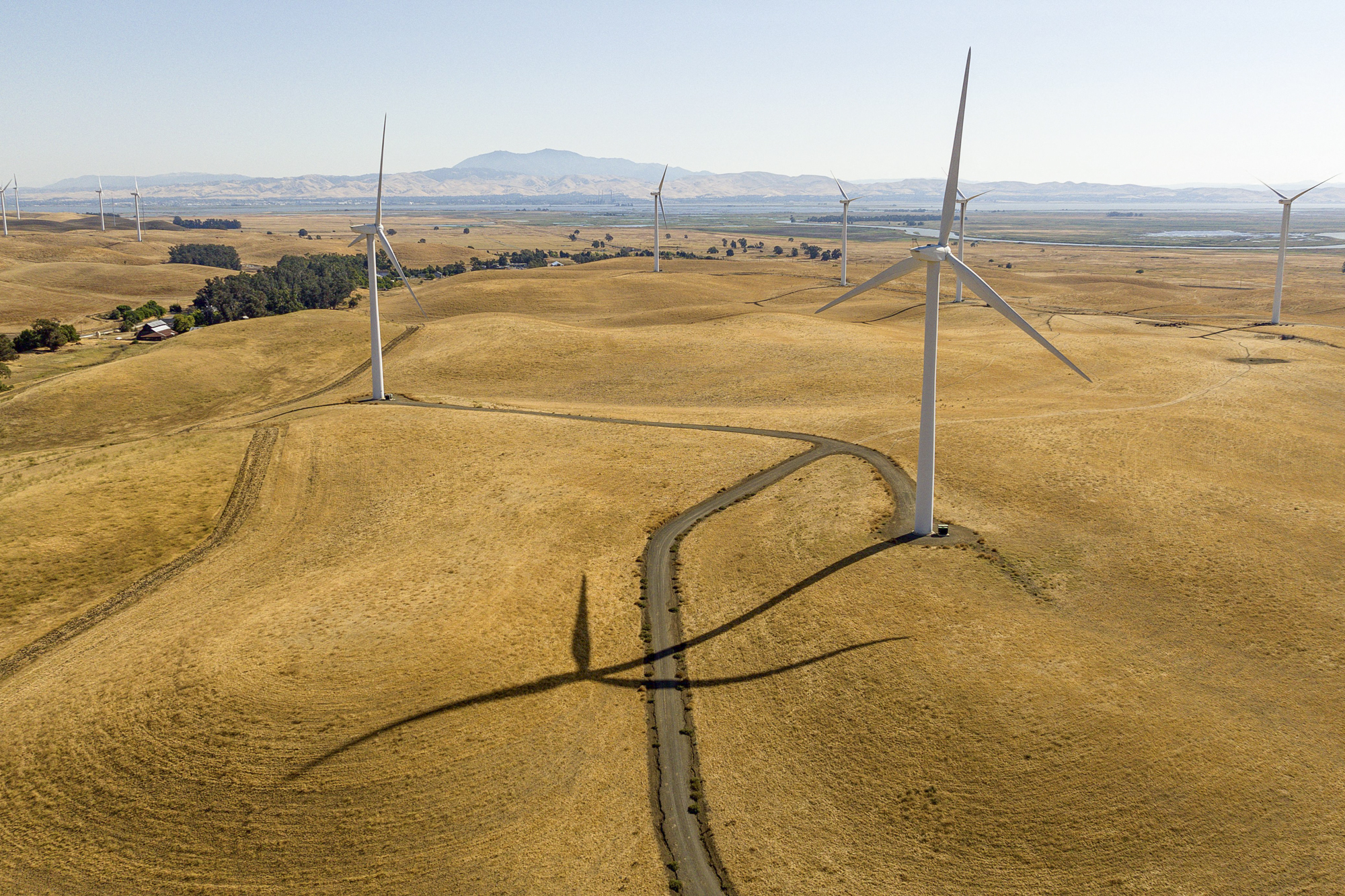 Windmills atop golden hillsides with a large mountain in the distance.