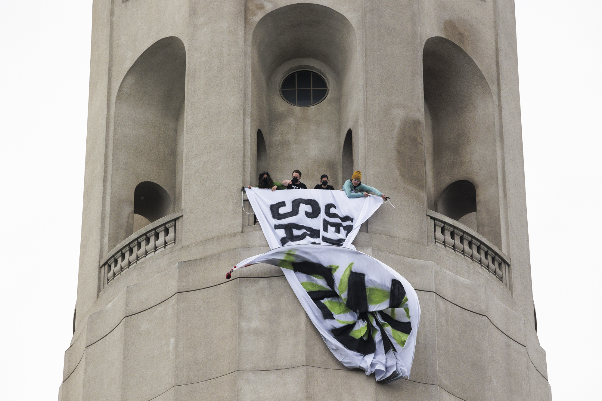 Protesters on a tower unfurling a banner.