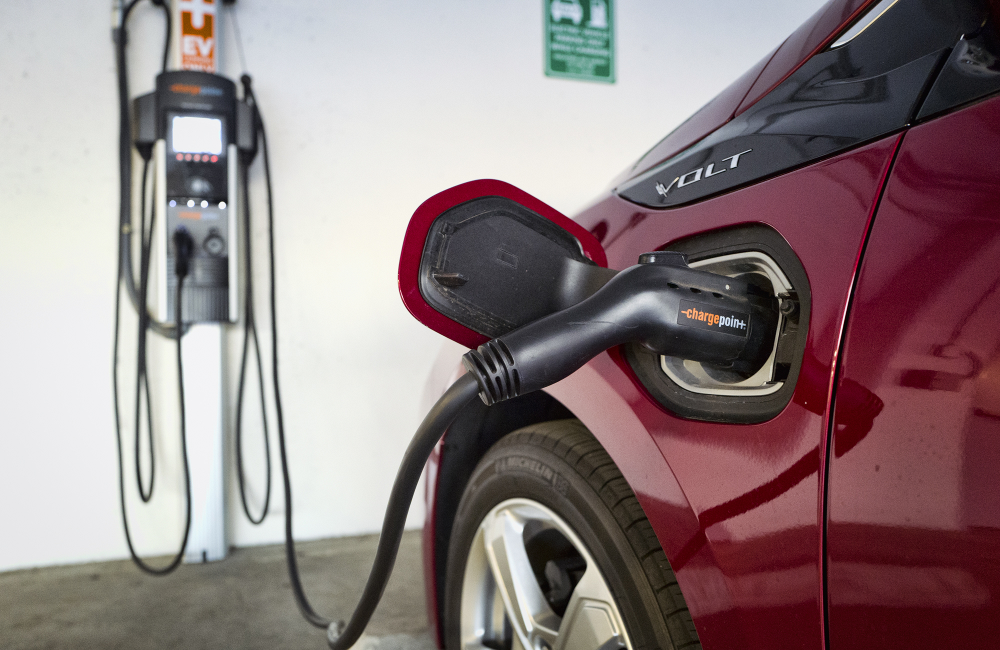 A red electric car is plugged in at a charging station.