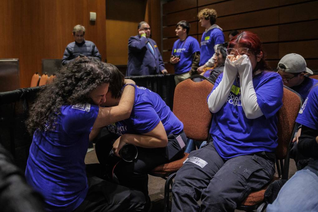 Several young people crying and hugging in an indoor setting.