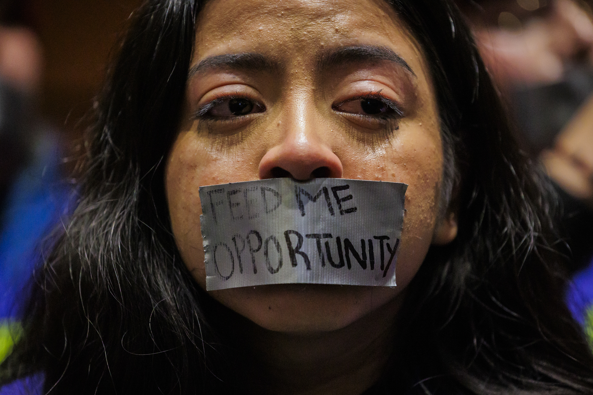 A young woman with gray tape covering her mouth, crying.