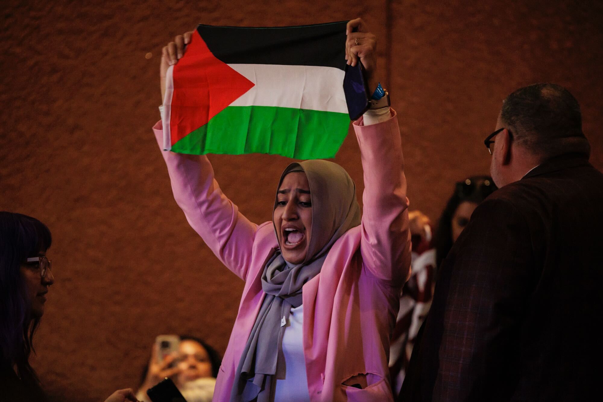 A protestor holds up a Palestinian flag in red, black, white and green colors inside an event where the Vice President was speaking in San Jose.