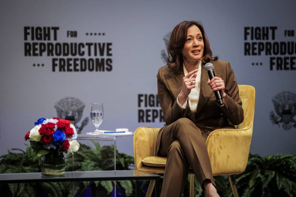 Vice President Kamala Harris is pictured sitting in a yellow seat on a stage.